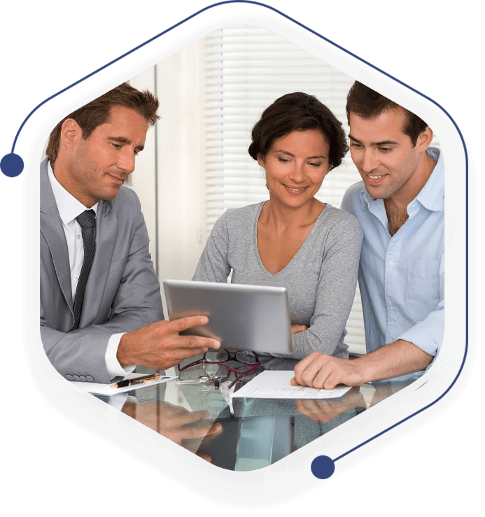 Three people are sitting around a table looking at a laptop.